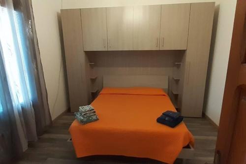 ein orangefarbenes Bett in einem kleinen Zimmer mit Schränken in der Unterkunft Casa Aida in Nurachi