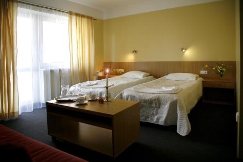 a hotel room with two beds and a table at Restoranas - Svečių Namai - Restaurant - Guest House Perkūnkiemis in Elektrėnai