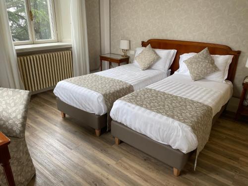 a hotel room with two beds and a chair at Palace Grand Hotel Varese in Varese