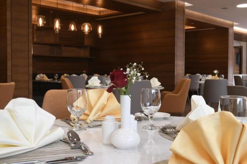 a dining room with a table with flowers on it at Golden Tulip Riyadh Convention and Exhibition Center in Riyadh
