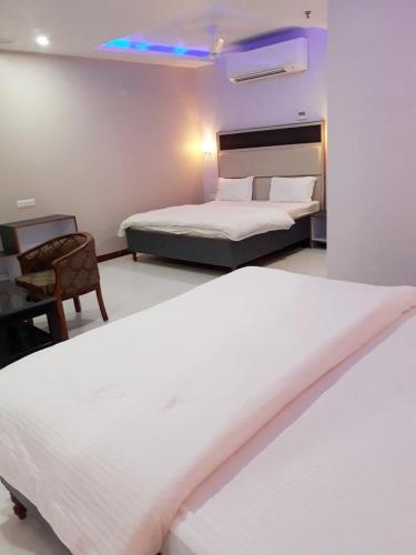 a hotel room with two beds and a chair at Hotel Abhilasha in Giriak