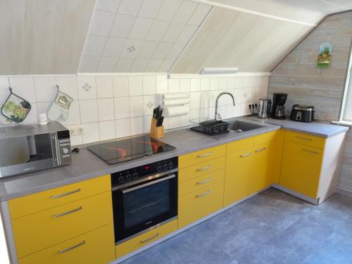 a kitchen with yellow cabinets and a microwave at Ferienwohnung Bauer Alter Hammer in Schmiedefeld am Rennsteig