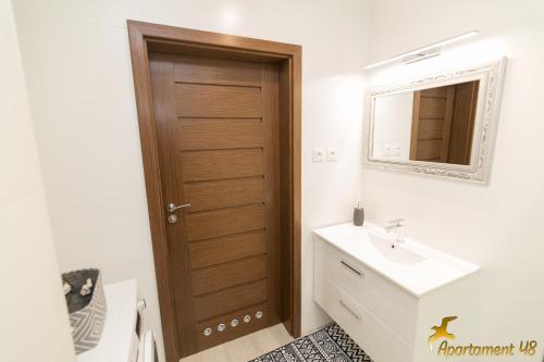 Un baño con puerta de madera y lavabo. en APARTAMENT 48 HEL, en Hel