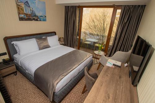 a bedroom with a bed and a desk and a television at Brezovica Hotel & SPA in Brezovicë