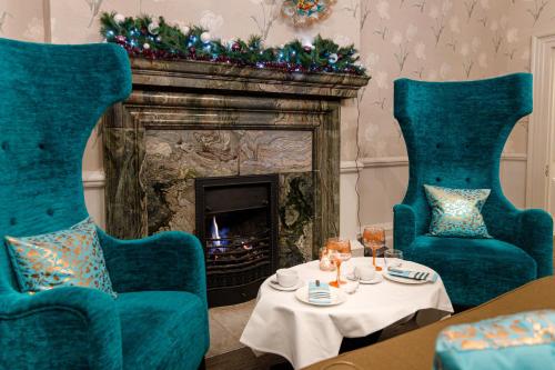 a living room with two blue chairs and a fireplace at Barnett Hill Hotel in Guildford