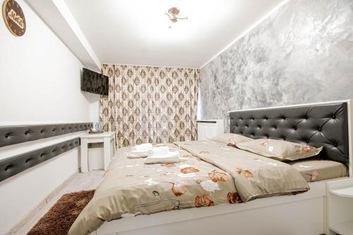 a bedroom with a large bed with a leather headboard at Cazare Moldi Btt in Câmpulung Moldovenesc