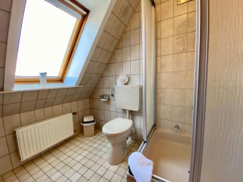 a bathroom with a toilet and a tub and a window at Haus Nicole in Cuxhaven