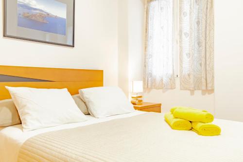 um quarto com uma cama branca e toalhas amarelas em Harmony Apartment no Funchal