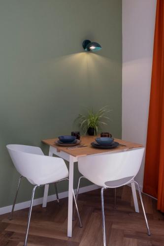 une table de salle à manger avec deux chaises blanches et une lumière dans l'établissement Kwadijkerbos, à Kwadijk