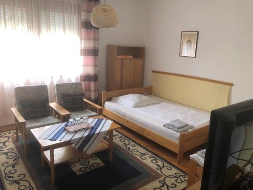 1 dormitorio con cama, mesa y TV en Kertész Rózsa Vendégház, en Nagykanizsa