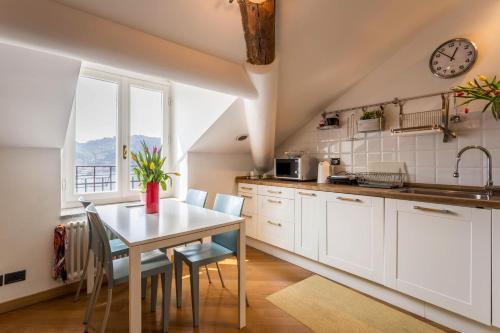 Una cocina con gabinetes blancos y una mesa con sillas. en Attico Vista Lago, en Como