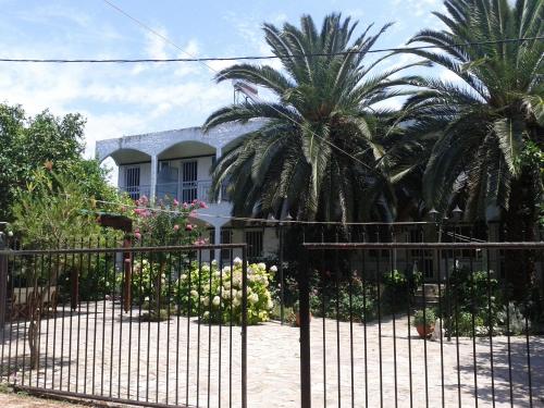 einen schmiedeeisernen Zaun vor einem Haus mit Palmen in der Unterkunft Margarita Apartments in Preveza