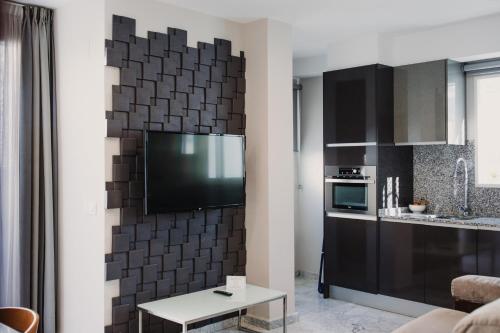 a kitchen with a black tile wall with a tv at Citizentral Gascons in Valencia