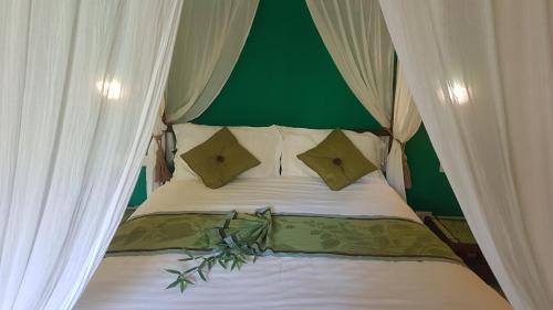 a bed with white curtains and a green wall at Tacacori EcoLodge in Alajuela City