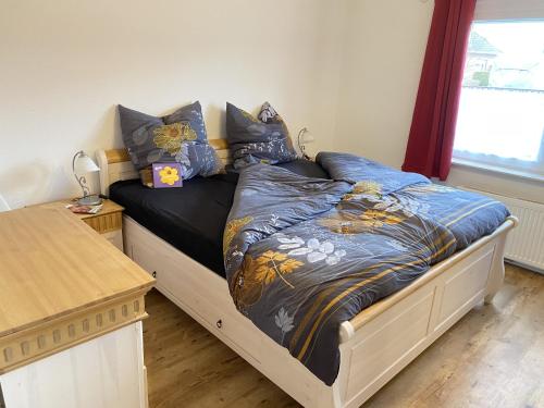 ein Schlafzimmer mit einem Bett mit blauer Decke und einem Fenster in der Unterkunft Ferienhaus Carpe diem in Krummhörn
