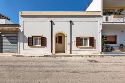 a white building with a door and two windows at Dimore Bonafede by BarbarHouse in Maruggio