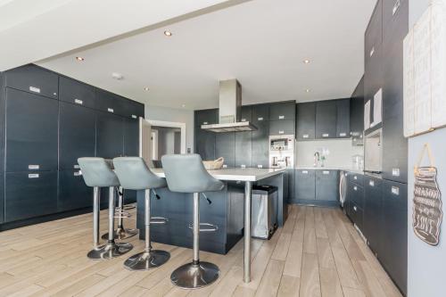 a kitchen with blue cabinets and a kitchen island with stools at Ocean View,Kinsale, Hosted by Exquisite holiday homes, sleeps 22 in Kinsale