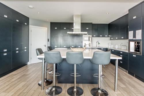 a kitchen with black cabinets and a kitchen island with bar stools at Ocean View,Kinsale, Hosted by Exquisite holiday homes, sleeps 22 in Kinsale