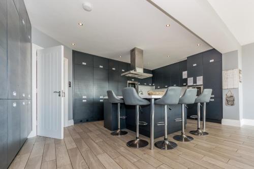 a kitchen with black cabinets and bar stools at Ocean View,Kinsale, Hosted by Exquisite holiday homes, sleeps 22 in Kinsale