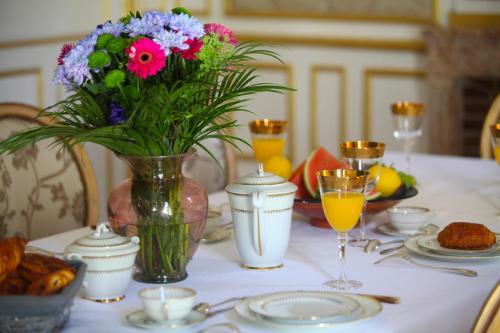 Ein Tisch mit einer Vase mit Blumen und Gläsern mit Orangensaft in der Unterkunft Château de Corcelle - Chambres et table d'hôtes in Châtenoy-le-Royal
