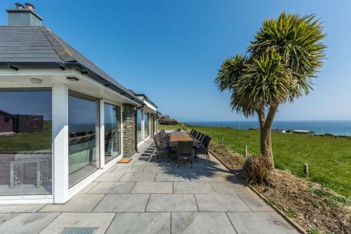 a porch of a house with a table and a palm tree at Ocean View,Kinsale, Hosted by Exquisite holiday homes, sleeps 22 in Kinsale