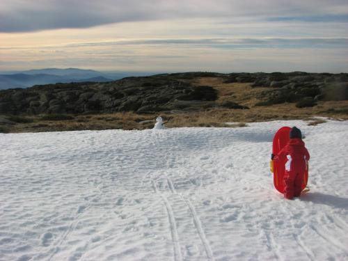a child is standing in the snow with a snowboard at Sambuc'asa - Serra da Estrela in Sabugueiro