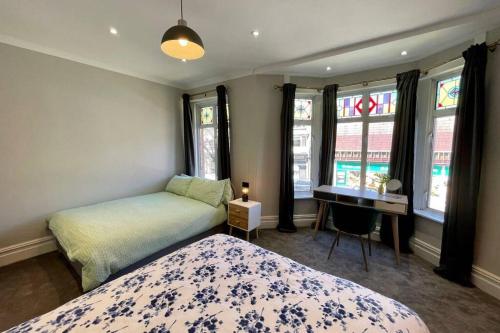 1 dormitorio con 1 cama, escritorio y ventanas en Large House near Victoria Park For Groups, 10 mins bus to City Centre, en Cardiff