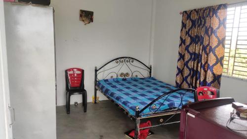 1 dormitorio pequeño con 1 cama y 1 silla en Vamoose Murti Homestay, en Chālsa Mahābāri