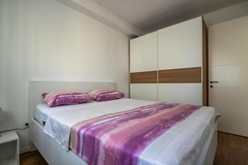 um quarto com uma cama grande com lençóis roxos e brancos em La Perla Jacuzzi em Murter