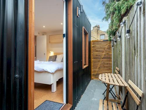 Cette chambre comprend une chambre, un lit et un banc. dans l'établissement Pass the Keys Whitstable Tiny house - a secret getaway!, à Whitstable