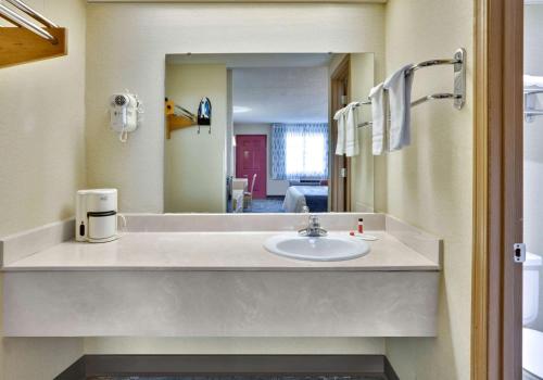 Days Inn & Suites by Wyndham Bentonville في بنتونفيل: حمام مع حوض ومرآة