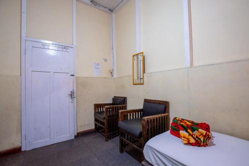 a room with three chairs and a bed and a door at Hotel Jogja Bukittinggi in Bukittinggi