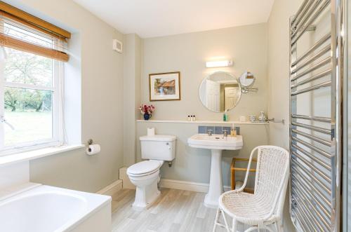 a bathroom with a sink and a toilet and a mirror at Stable Cottage - Milton Lilbourne in Pewsey