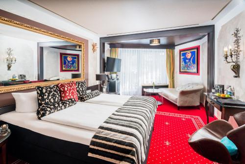 a bedroom with a large bed with a red carpet at Alpin & Wellness Resort Ludwig Royal in Oberstaufen