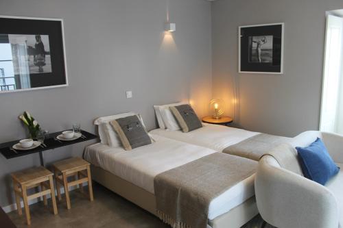 a bedroom with two beds and a table and a chair at CASA DAS QUATRO CABEÇAS in Setúbal