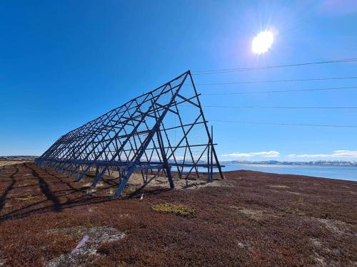a electricity transmission tower on top of a field at Varangertunet Aldonen Apartment in Vadsø