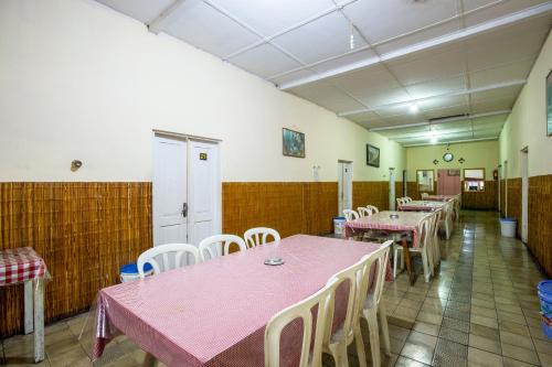 a dining room with pink tables and white chairs at Hotel Jogja Bukittinggi in Bukittinggi