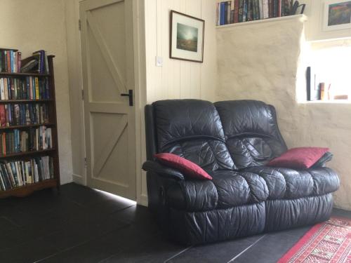 a black leather chair with two red pillows in a living room at Comraich in Tokavaig