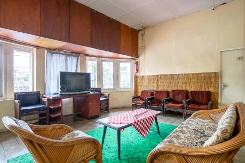 a living room with a tv and chairs and a table at Hotel Jogja Bukittinggi in Bukittinggi