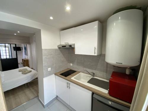 a kitchen with white cabinets and a sink and a bed at L'Arche de Porquerolles in Porquerolles