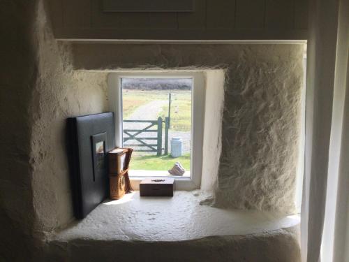 a window in a wall with a view of a gate at Comraich in Tokavaig