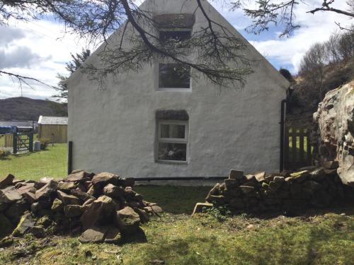 a white house with a pile of rocks in front of it at Comraich in Tokavaig