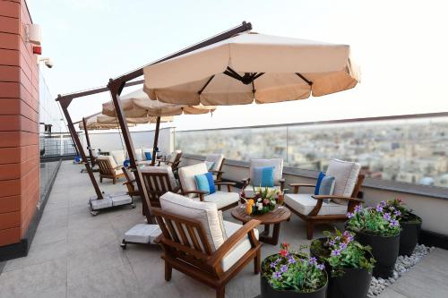 a patio with chairs and an umbrella on a roof at Golden Tulip Riyadh Convention and Exhibition Center in Riyadh