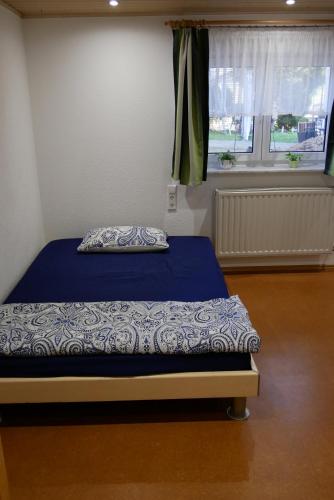 1 dormitorio con cama con sábanas azules y ventana en FerienZimmer en Niederstetten
