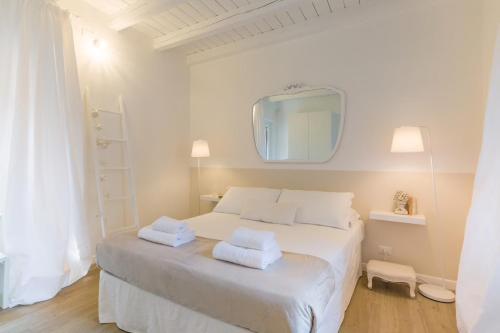 - une chambre blanche avec un lit blanc et un miroir dans l'établissement Uno splendido punto a Verona!!, à Vérone