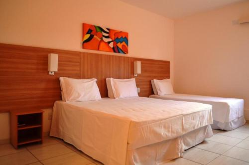 a hotel room with two beds and a painting on the wall at Hotel Áster in Alagoinhas