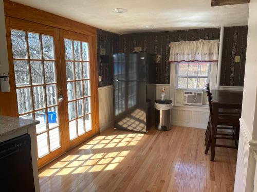 a kitchen with wooden floors and windows and a refrigerator at The Cottages at Harvey Lake in Northwood