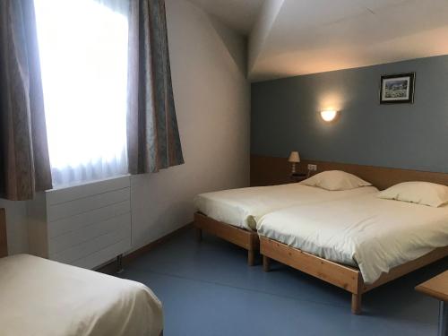 2 camas en una habitación pequeña con ventana en Hôtel Saint Augustin, en Mittelbronn