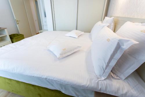 a white bed with white pillows on it at Pension Carmen`s Mansion A in Sinaia