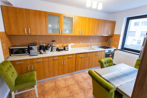 a kitchen with wooden cabinets and a table with green chairs at Pension Carmen`s Mansion A in Sinaia